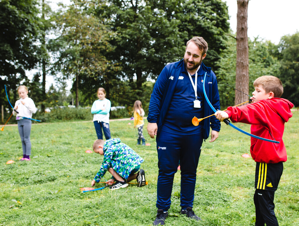 Premier Education coach teaching children how to perform archery 