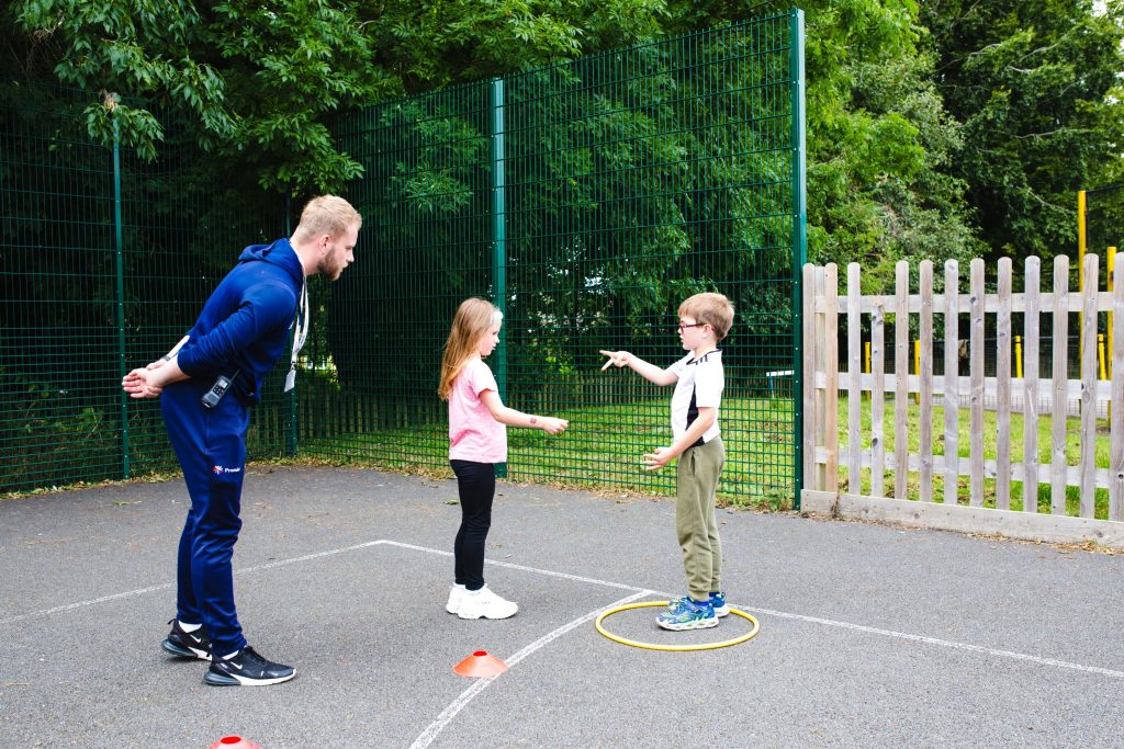 Premier Education coach with two children at a summer camp activity 