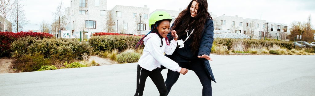 Young girl practices her rolling skating with a Premier Education Activity Professional.