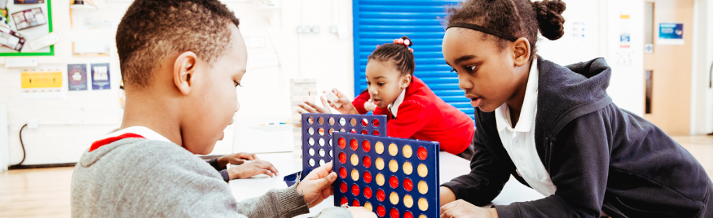 Children concentrating on a game of connect 4 during Premier Education Wraparound Care at their school in London.