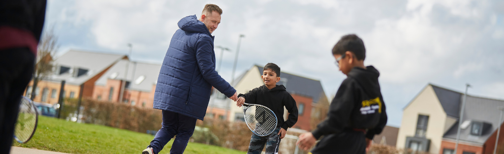 Premier Education coach joining in with a tennis session.