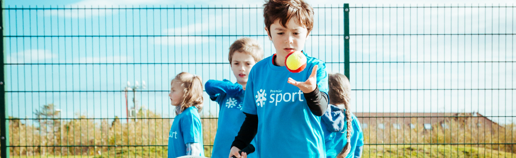 A child serving a tennis ball at a Premier Education activity course